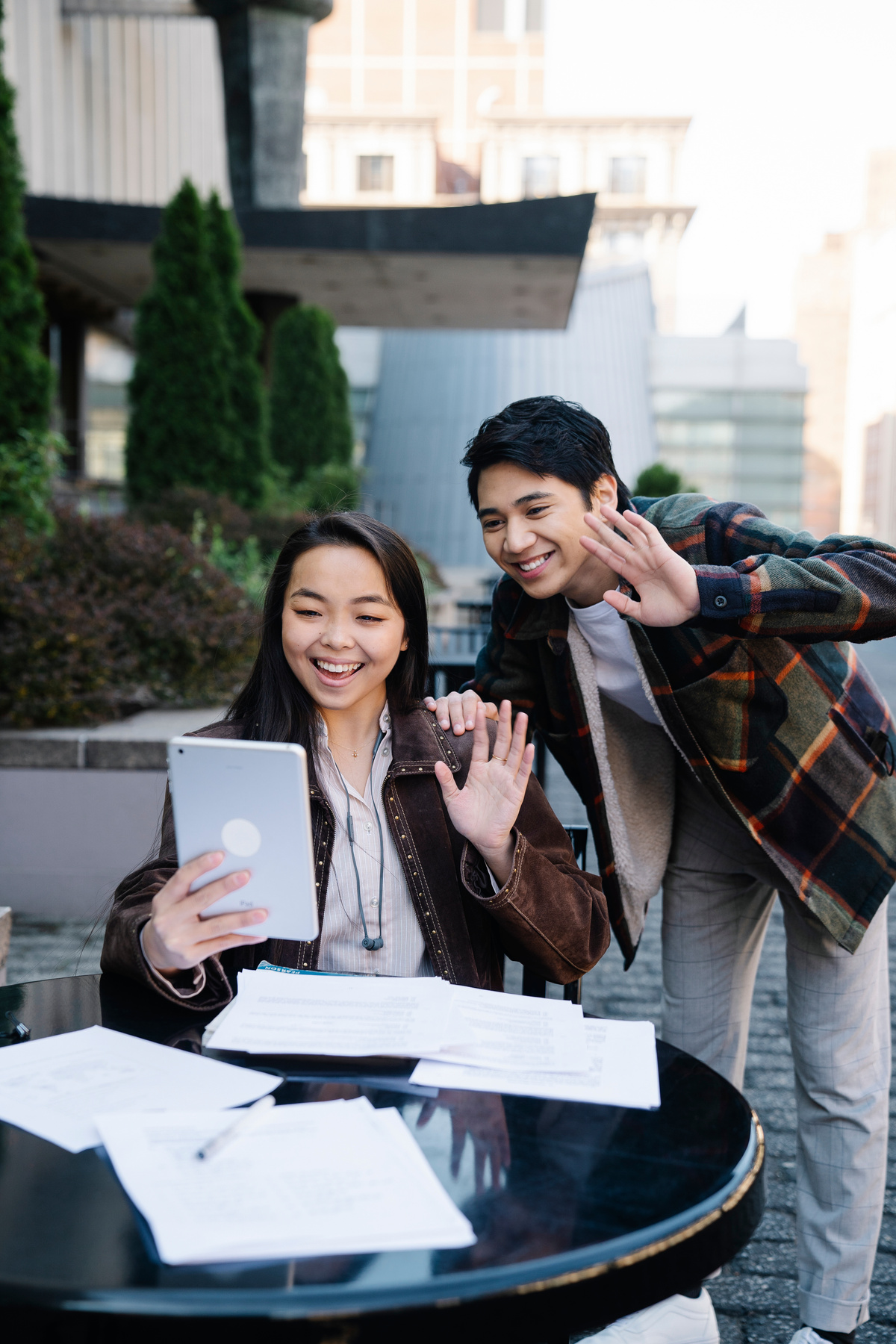 Two Students Waving Cheerfully at Digital Tablet During a Video Call