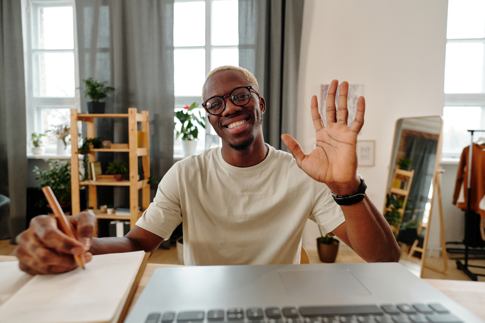 Man with Eyeglasses Smiling while Waving a Hand